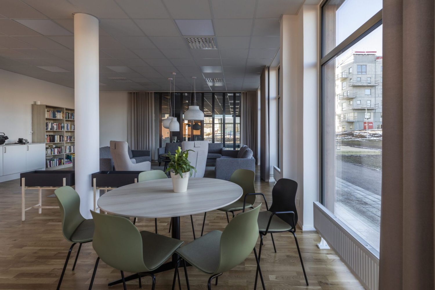 Ett rum med runt bord och gröna stolar i en BRF.
